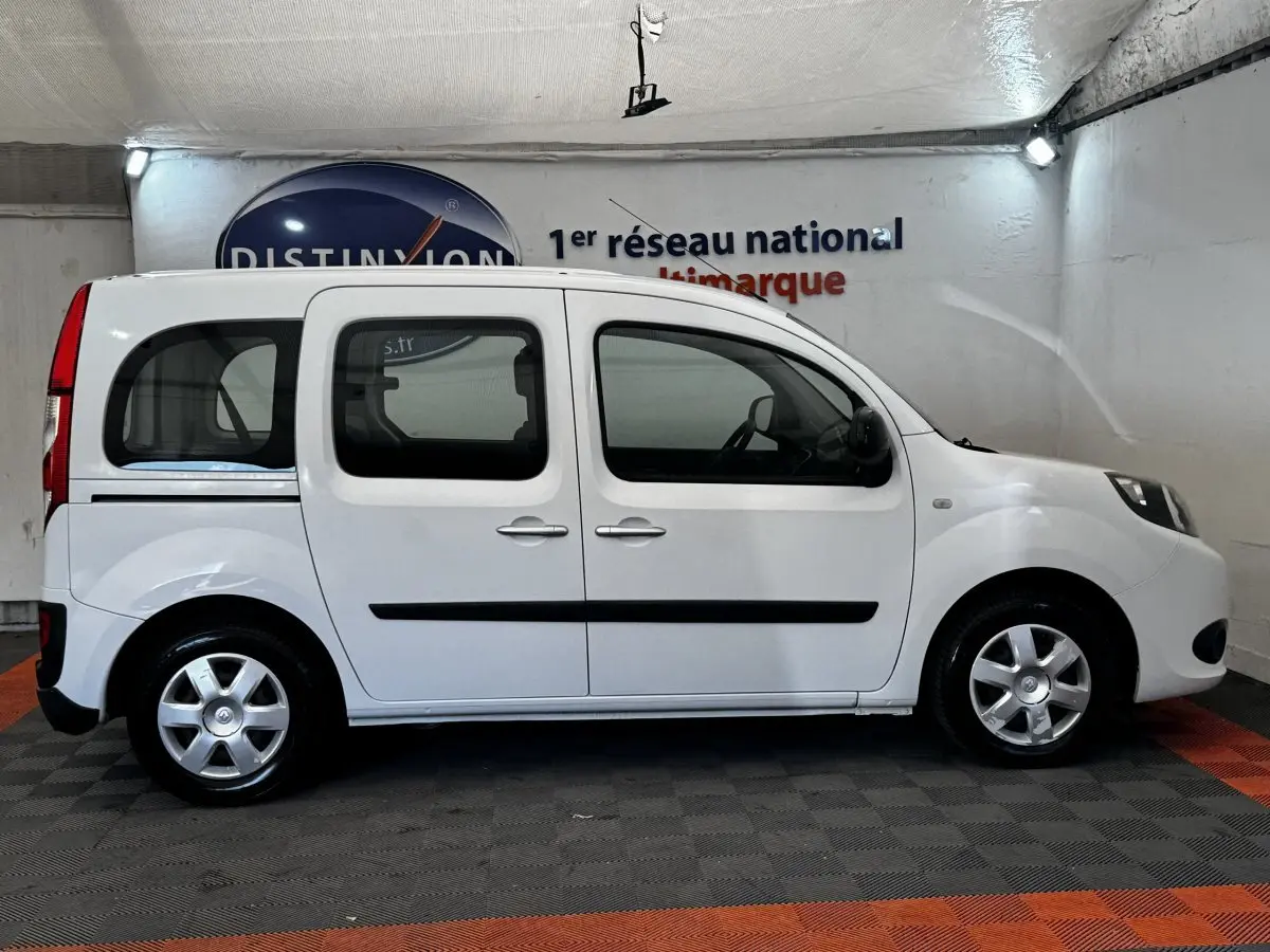 Profil latéral droit d’un Renault Kangoo blanc 2016, version Zen, dans un showroom intérieur.