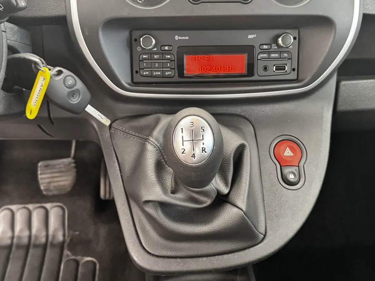 Vue rapprochée de la console centrale du Renault Kangoo blanc 2016, avec levier de vitesse manuel et radio affichant 102.40 MHz.