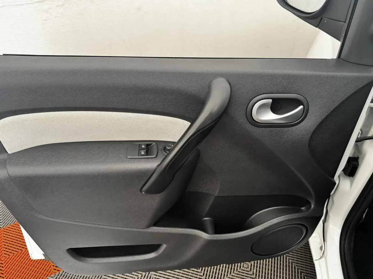 Vue rapprochée de la porte avant droite blanche du Renault Kangoo Zen 2016 avec poignée noire et commandes de vitres.
