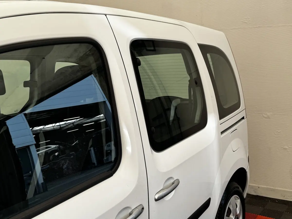Vue latérale droite du Renault Kangoo blanc 2016, mettant en valeur les vitres teintées et la porte coulissante arrière.