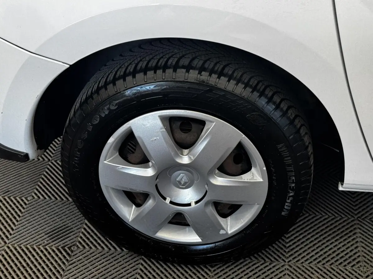 Gros plan sur la roue arrière droite d’un Renault Kangoo blanc, montrant le passage de roue et le pneu toutes saisons.