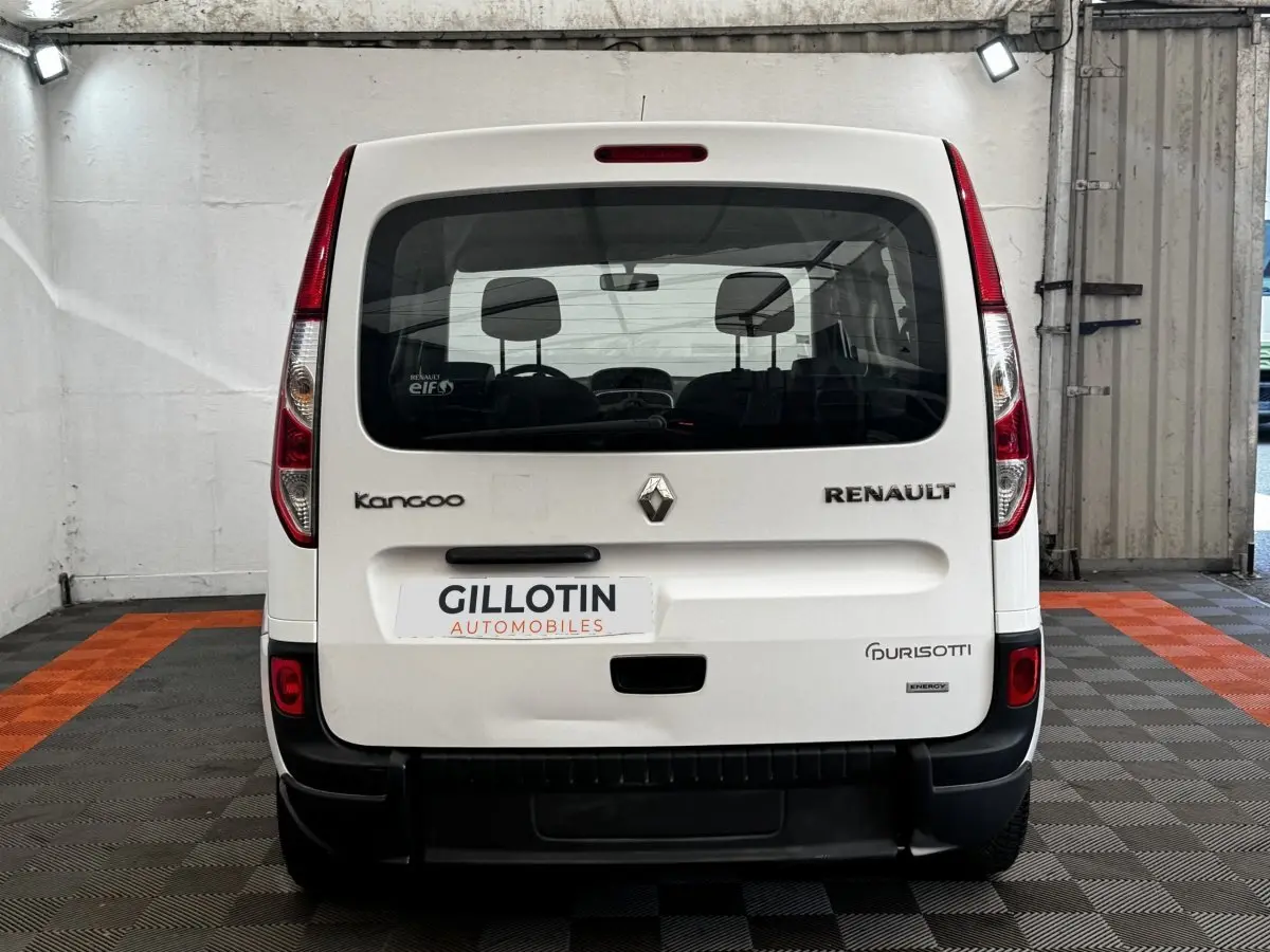 Vue arrière d’un Renault Kangoo blanc 2016 avec logos visibles et plaque d’un concessionnaire en intérieur.