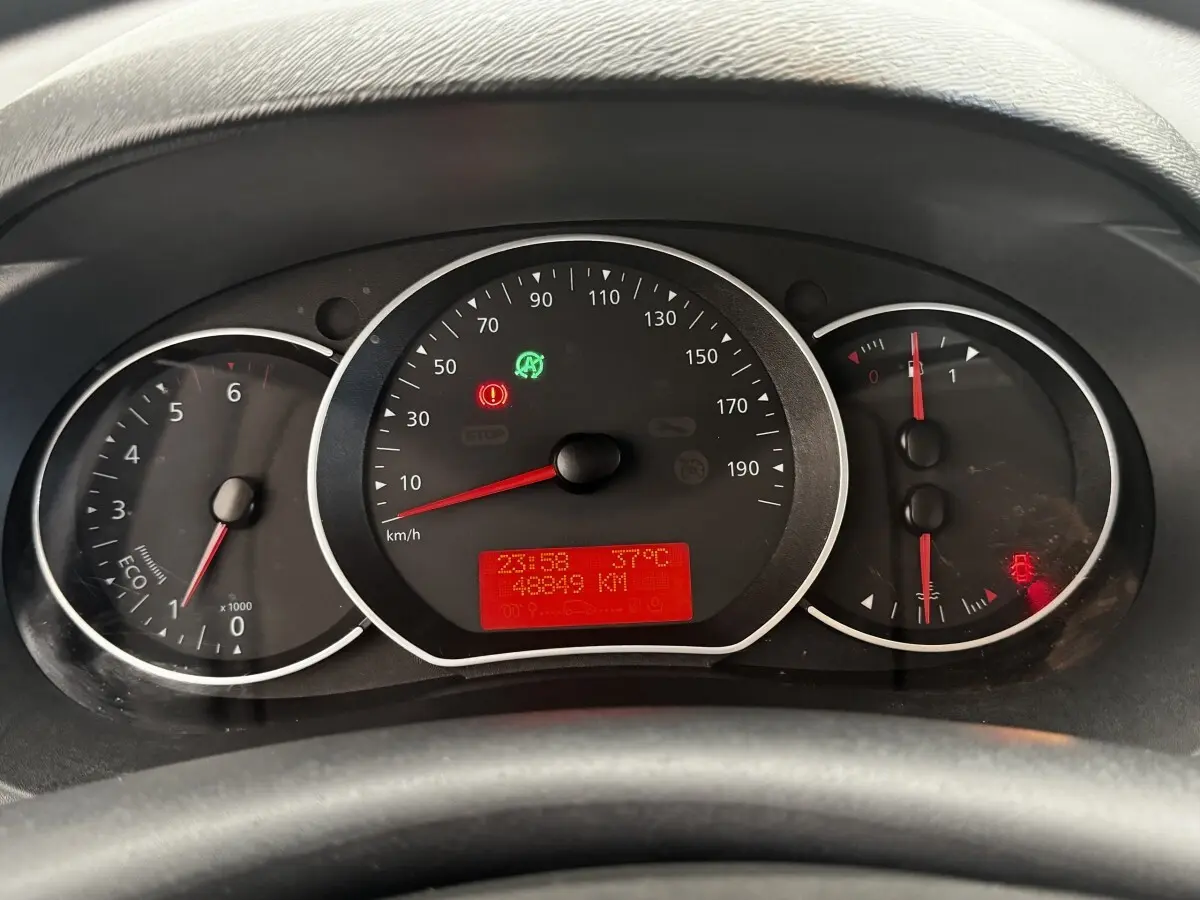 Vue rapprochée du tableau de bord du Renault Kangoo blanc 2016, affichant le compteur et les voyants allumés.