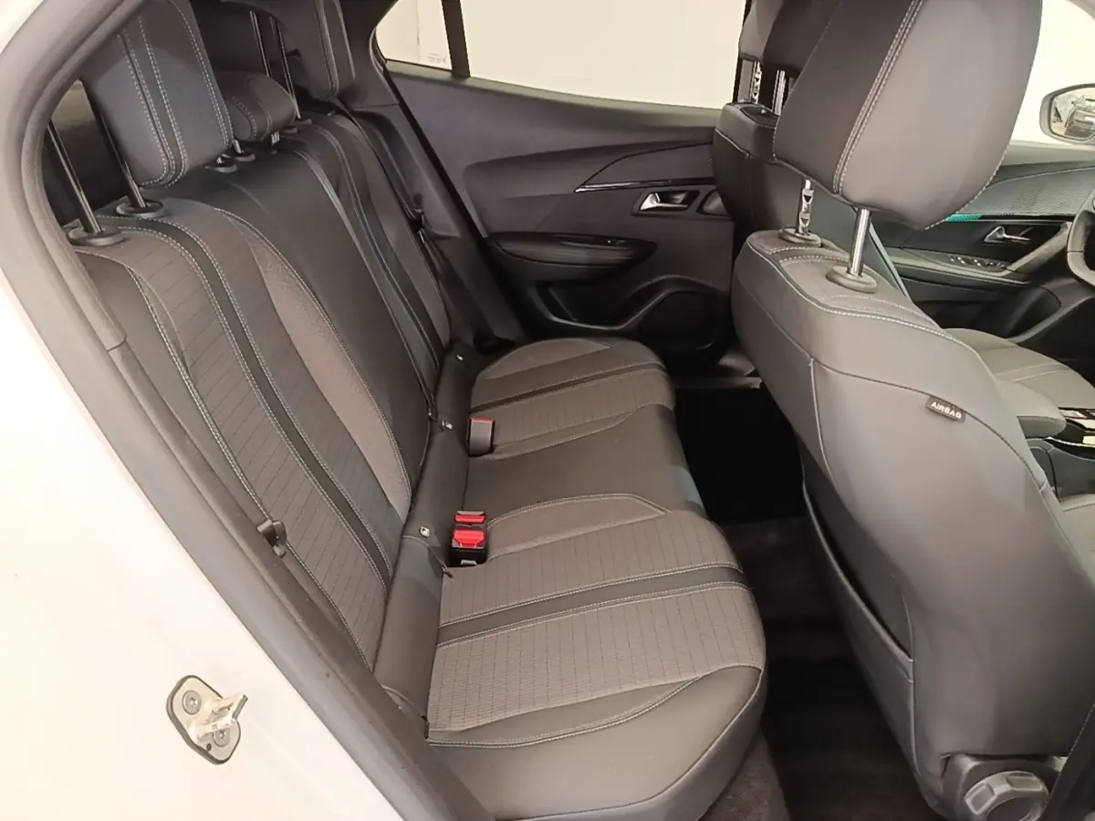 Vue intérieure côté gauche montrant la banquette arrière noire du Peugeot 2008 blanc de 2021 avec finitions tissu et cuir.