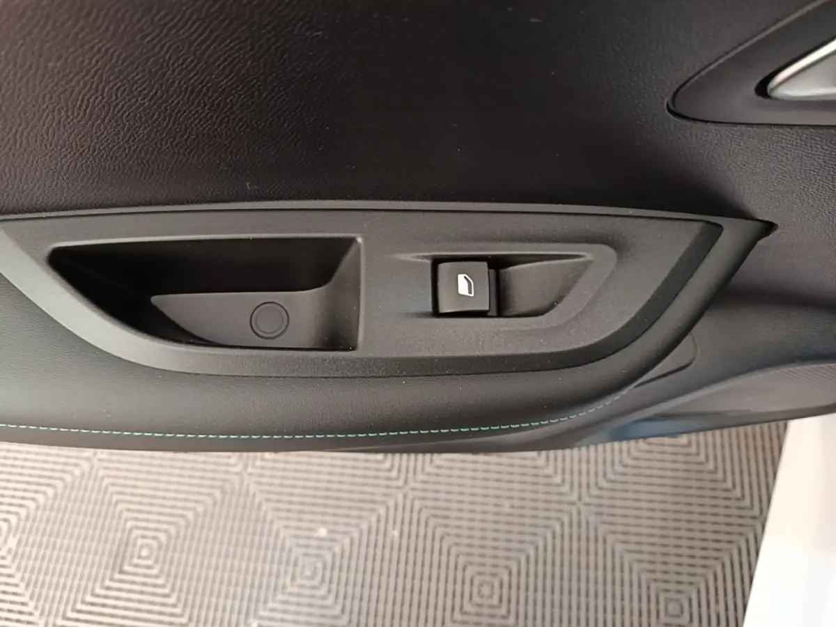 Poignée intérieure de porte côté droit du Peugeot 2008 blanc, avec bouton de verrouillage et surpiqûres bleues.