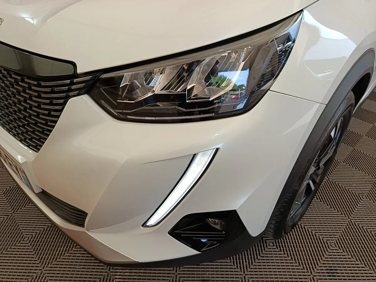 Gros plan sur l'avant droit blanc du Peugeot 2008 2021, mettant en valeur le phare LED et la calandre noire.