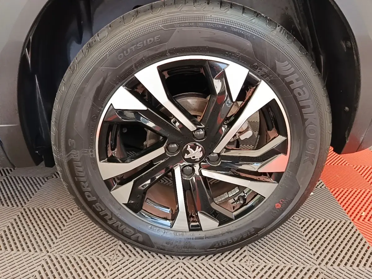 Gros plan sur la jante alliage noire et argentée avec logo Peugeot, montée sur pneu Hankook Ventus Prime 3.