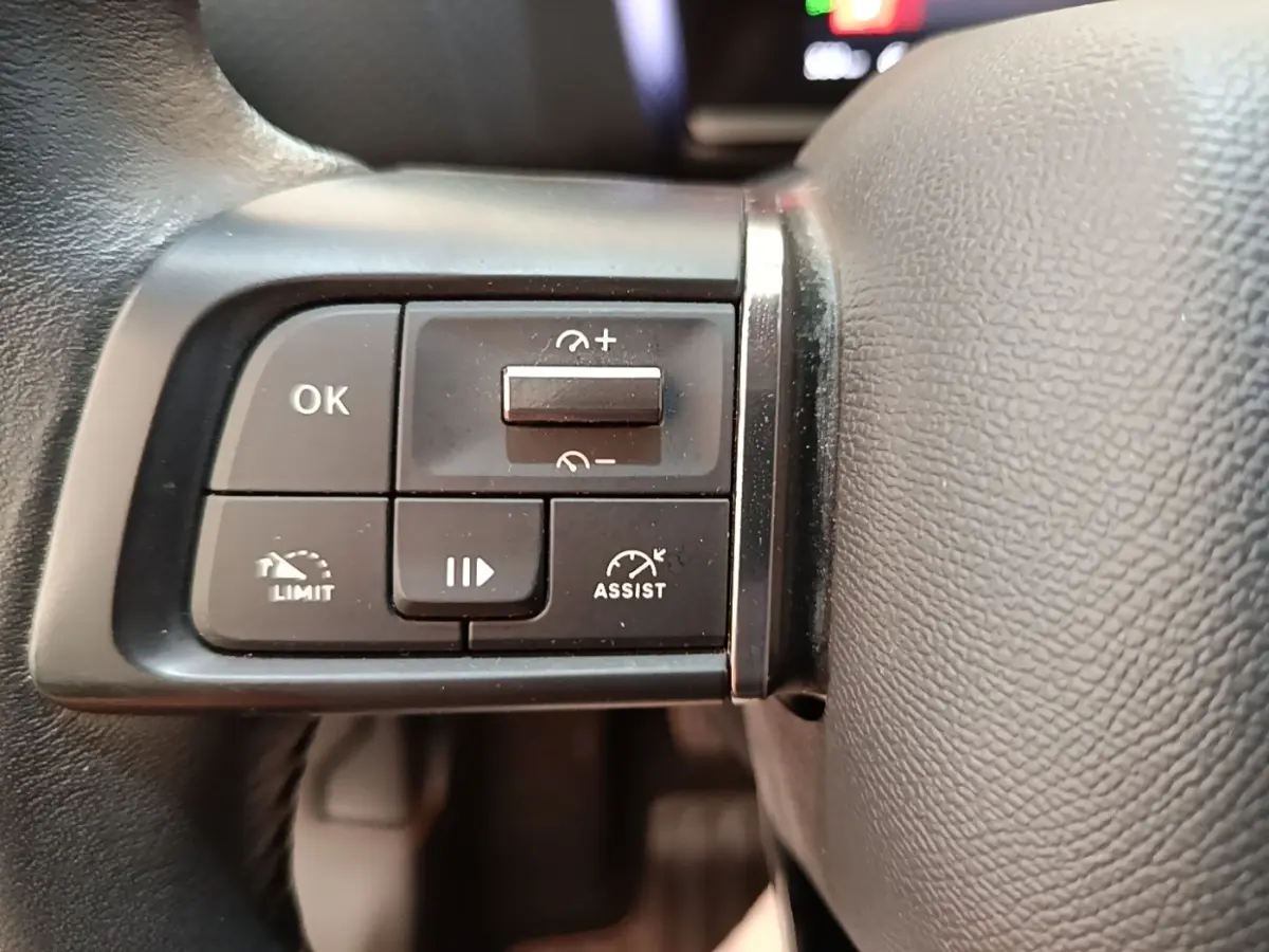 Gros plan sur les commandes noires multifonctions du volant cuir de la Citroën C4 gris clair, côté gauche.
