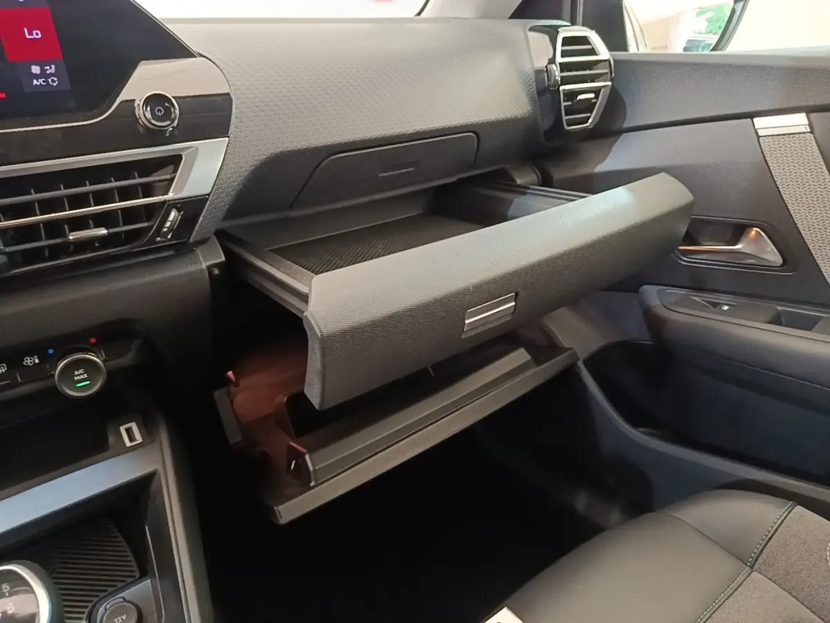 Vue intérieure côté passager de la Citroën C4 2021 gris clair, avec boîte à gants ouverte et tableau de bord moderne.