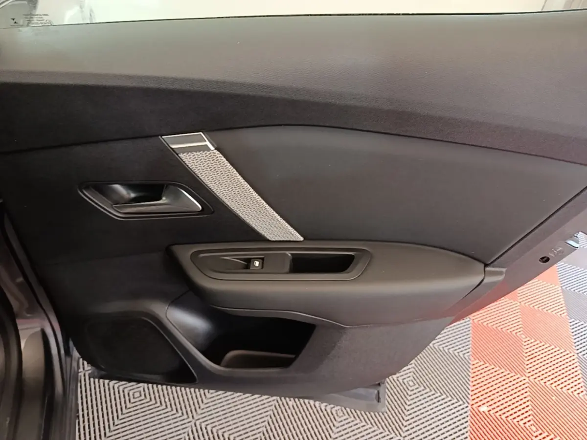 Vue intérieure côté gauche de la porte arrière d’une Citroën C4 gris clair avec poignée et commande de lève-vitre.