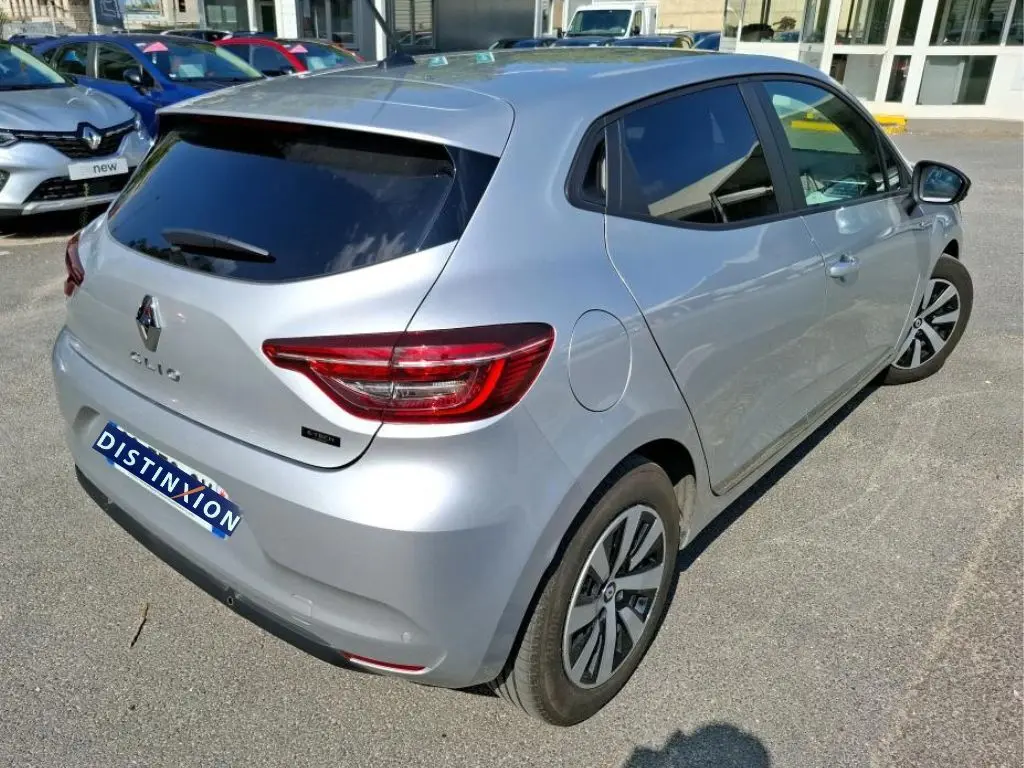 Vue 3/4 arrière droite d'une Renault Clio 1.6 E-Tech hybride gris platine avec feux arrière LED et jantes spécifiques.