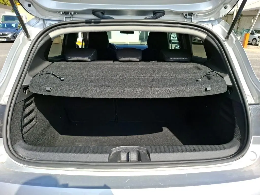 Coffre ouvert vu de l'arrière d'une Renault Clio 1.6 E-Tech gris platine, montrant la plage arrière et l'espace de chargement.