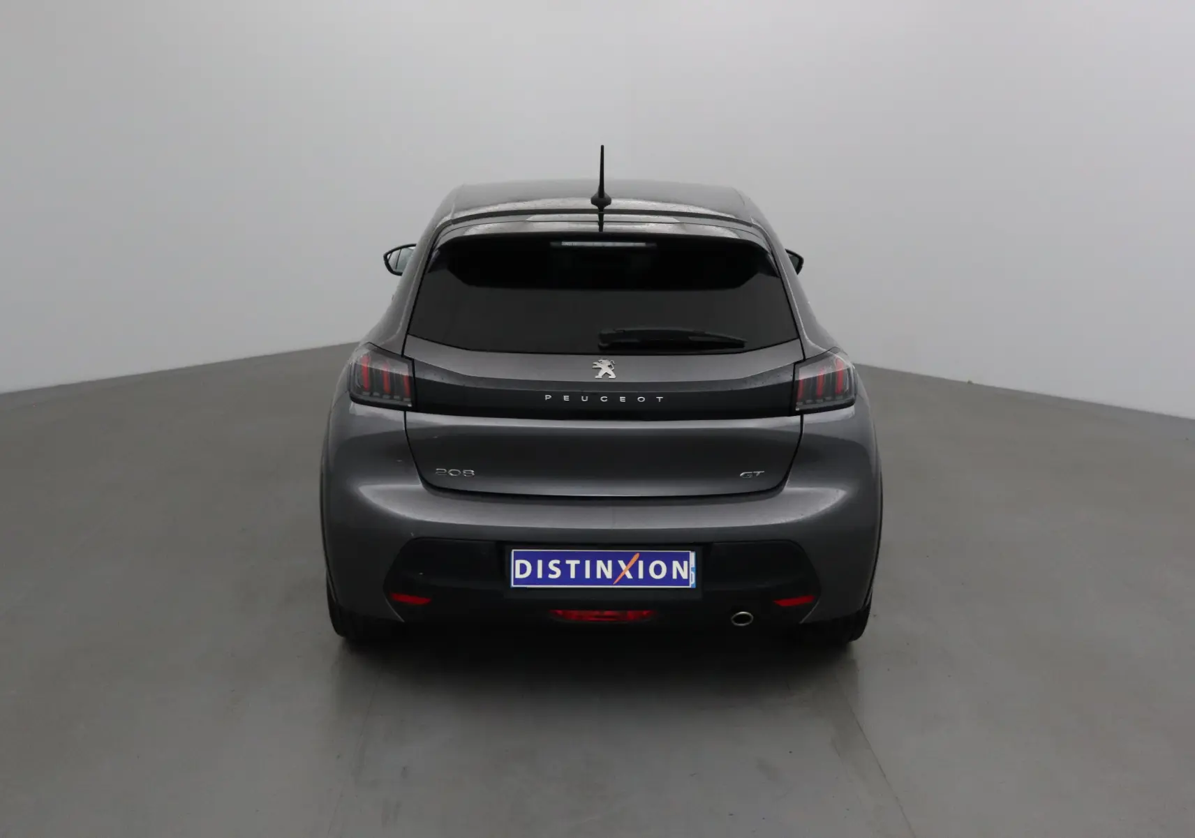 Vue arrière d'une Peugeot 208 GT 2023 gris platinium avec feux arrière à griffes et lunette arrière teintée.