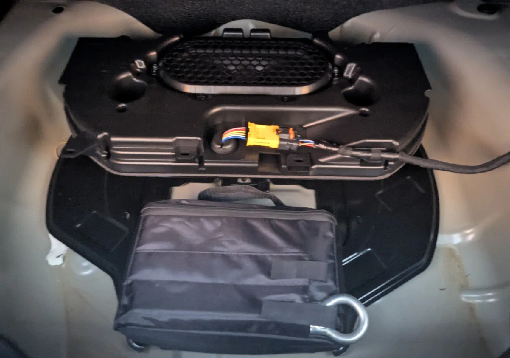 Gros plan sur le coffre de la Citroën C4 2024, montrant un rangement avec sac noir et câblage visible.