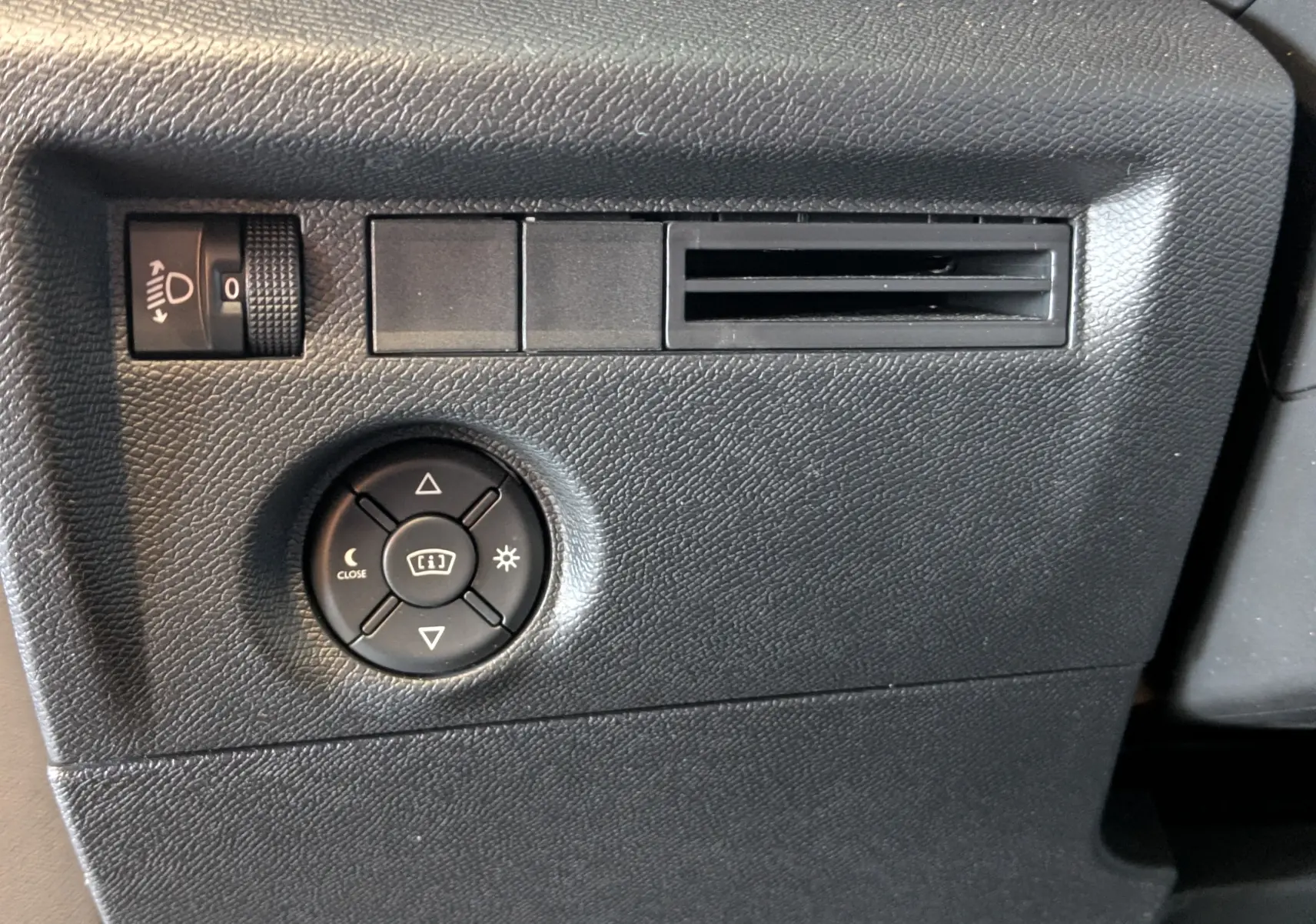 Détail du tableau de bord noir de la Citroën C4 2024 montrant les commandes d'éclairage et la sortie d'air latérale.