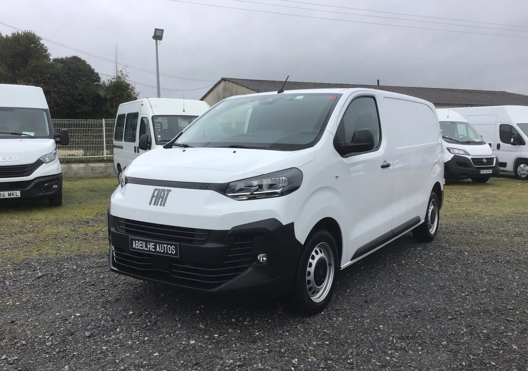 Vue 3/4 avant droite du FIAT Scudo Fourgon blanc 2024 avec pare-chocs noir et plaque de protection tôlée visible.