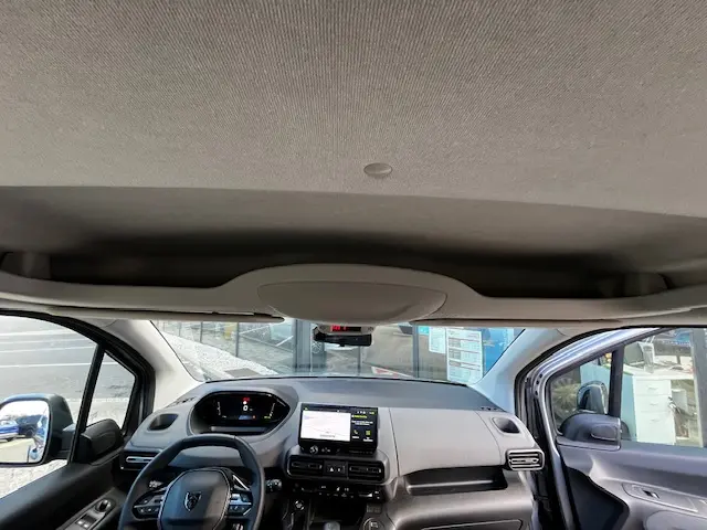 Vue intérieure avant du Peugeot Rifter gris foncé 2024, montrant le tableau de bord digital et l’écran central tactile.