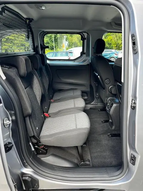 Vue intérieure côté droit des sièges arrière gris clair du Peugeot Rifter 1.5 BlueHDi 2024 avec séparation grillagée et fenêtre latérale.