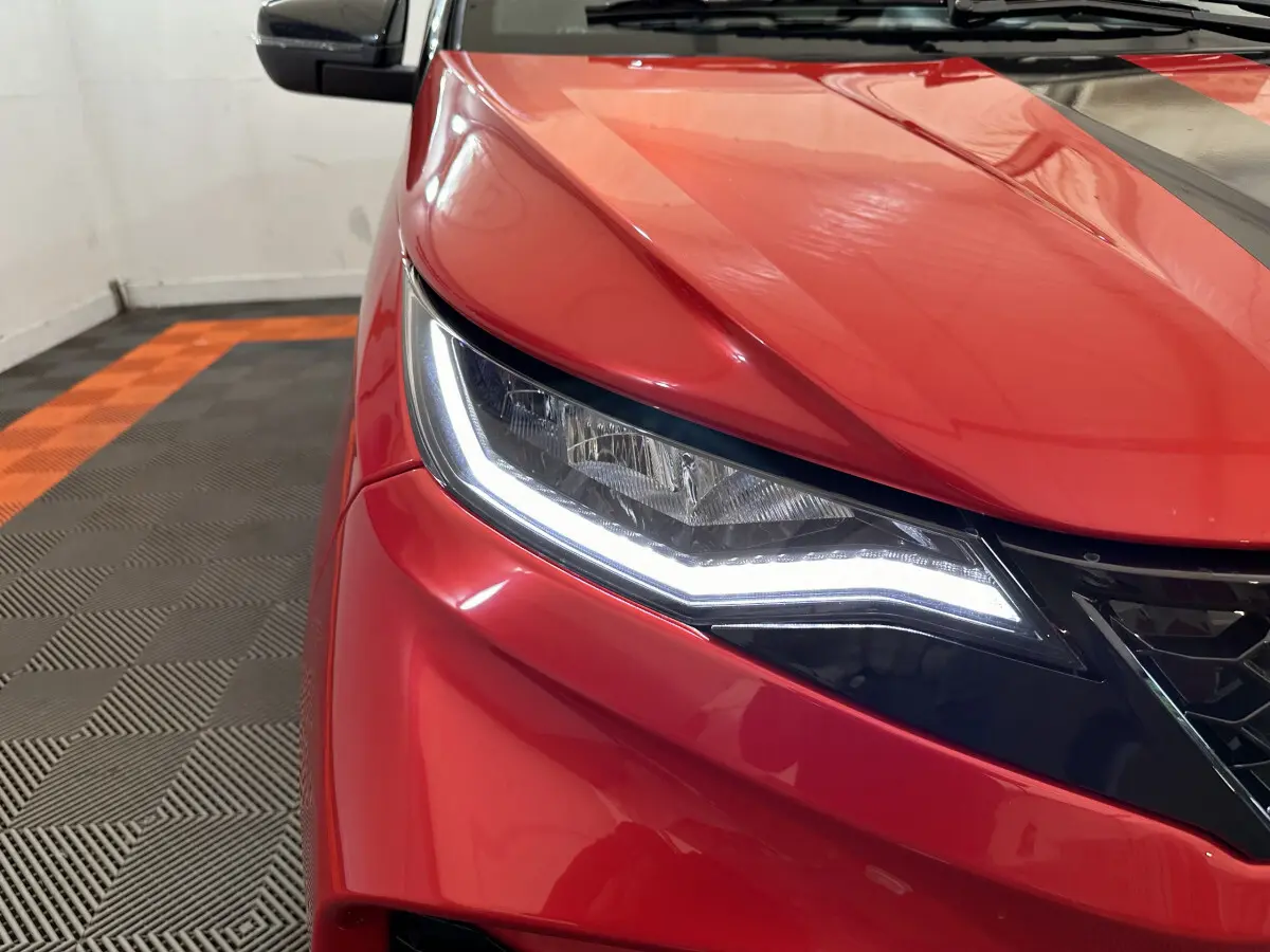 Gros plan sur l'avant gauche rouge de l'AIXAM AMBITION 0.5 CITY COUPE GTI avec phares LED allumés.