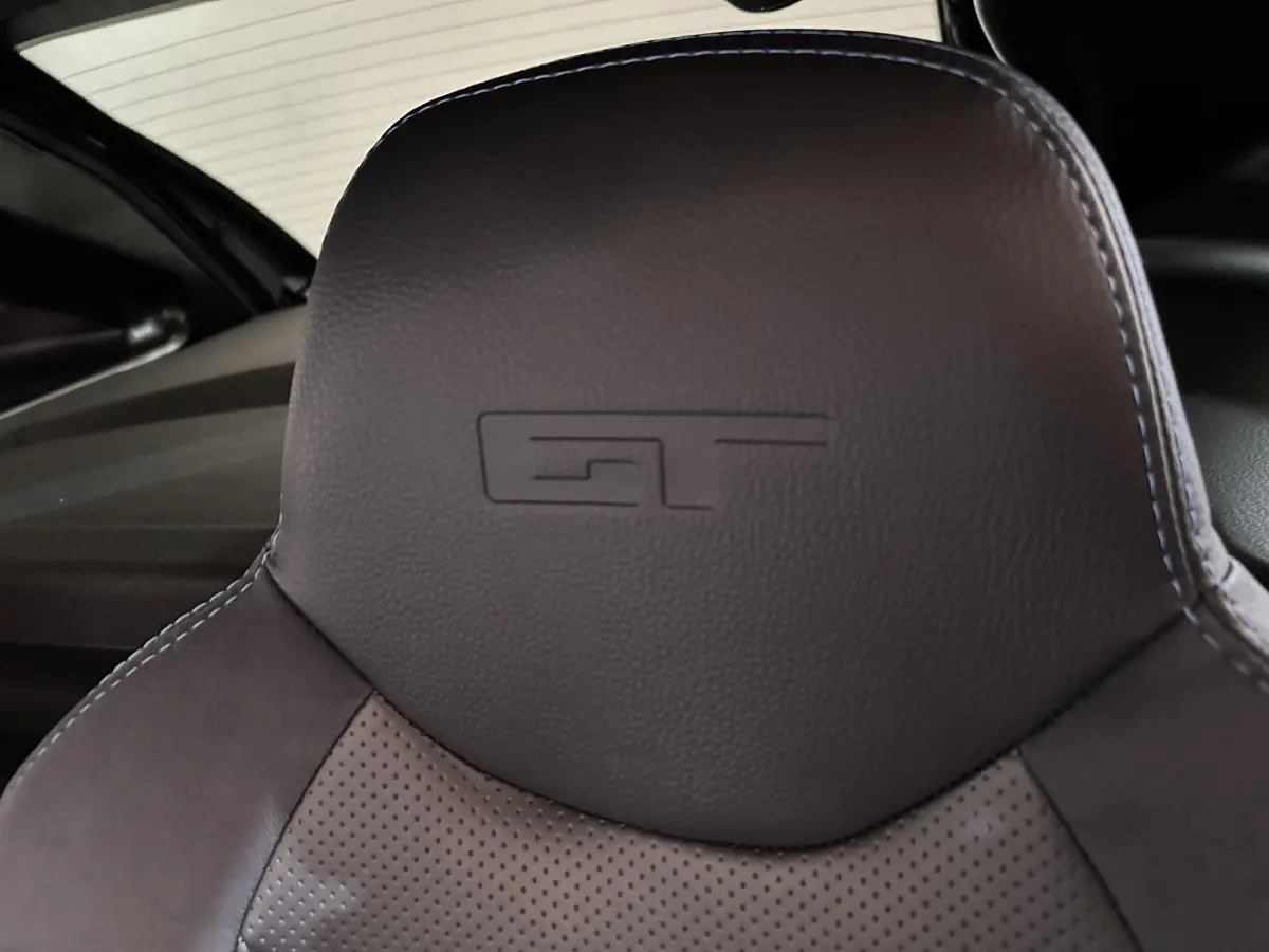 Gros plan sur l'appui-tête en cuir noir avec logo GT embossé, intérieur de l'AIXAM AMBITION 0.5 CITY COUPE GTI 2026.