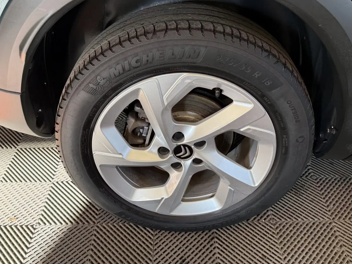Gros plan sur la roue avant gauche avec jante argentée et pneu Michelin du Citroën C5 Aircross bleu hybride.