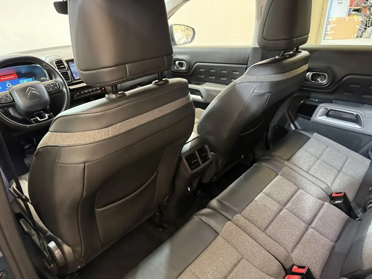 Vue intérieure arrière du Citroën C5 Aircross Hybrid avec sièges bi-matière gris et noir et tableau de bord visible à l'avant.