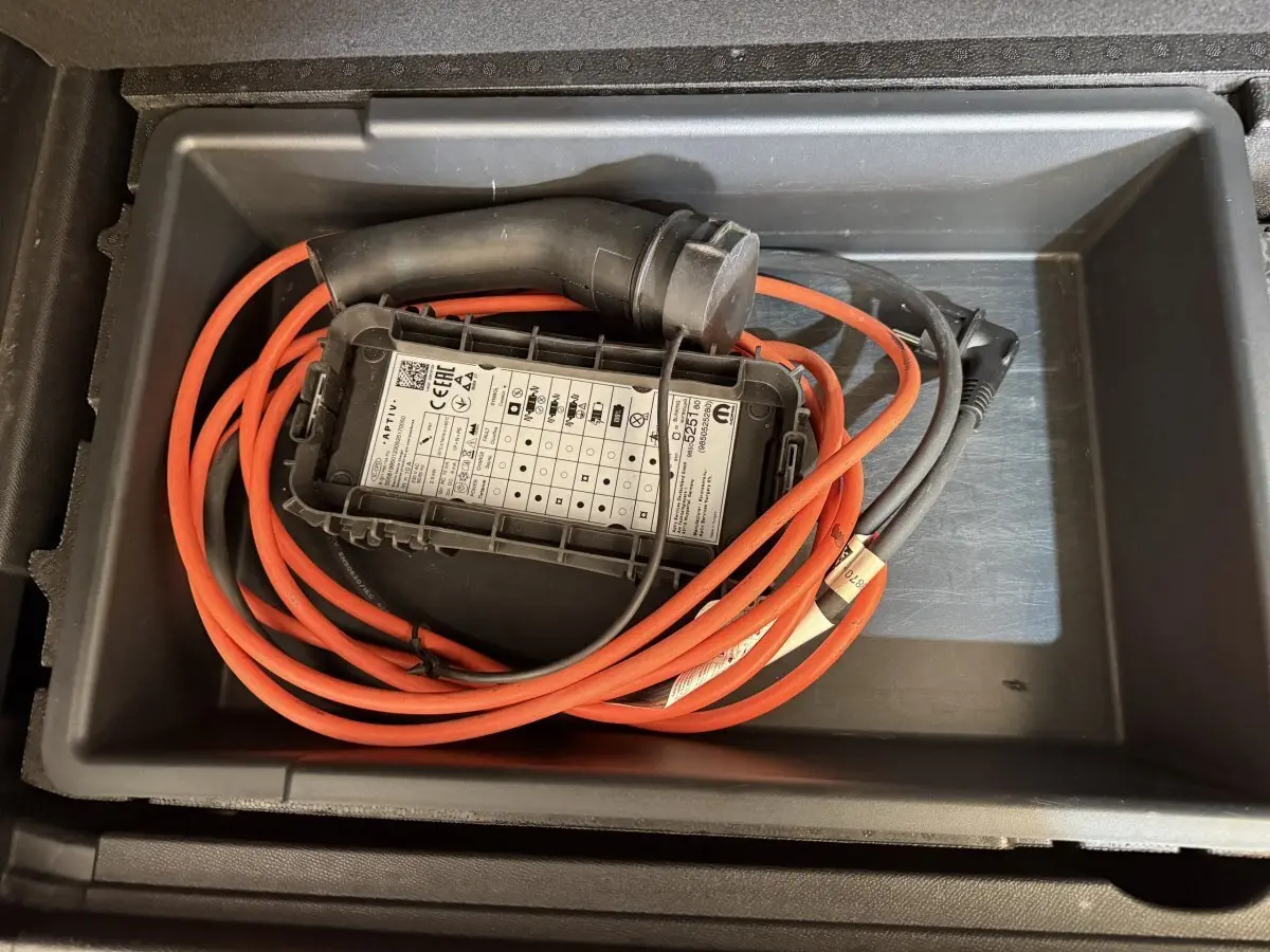Câble de recharge hybride rouge et noir rangé dans le coffre d’un Citroën C5 Aircross bleu, vue de dessus.