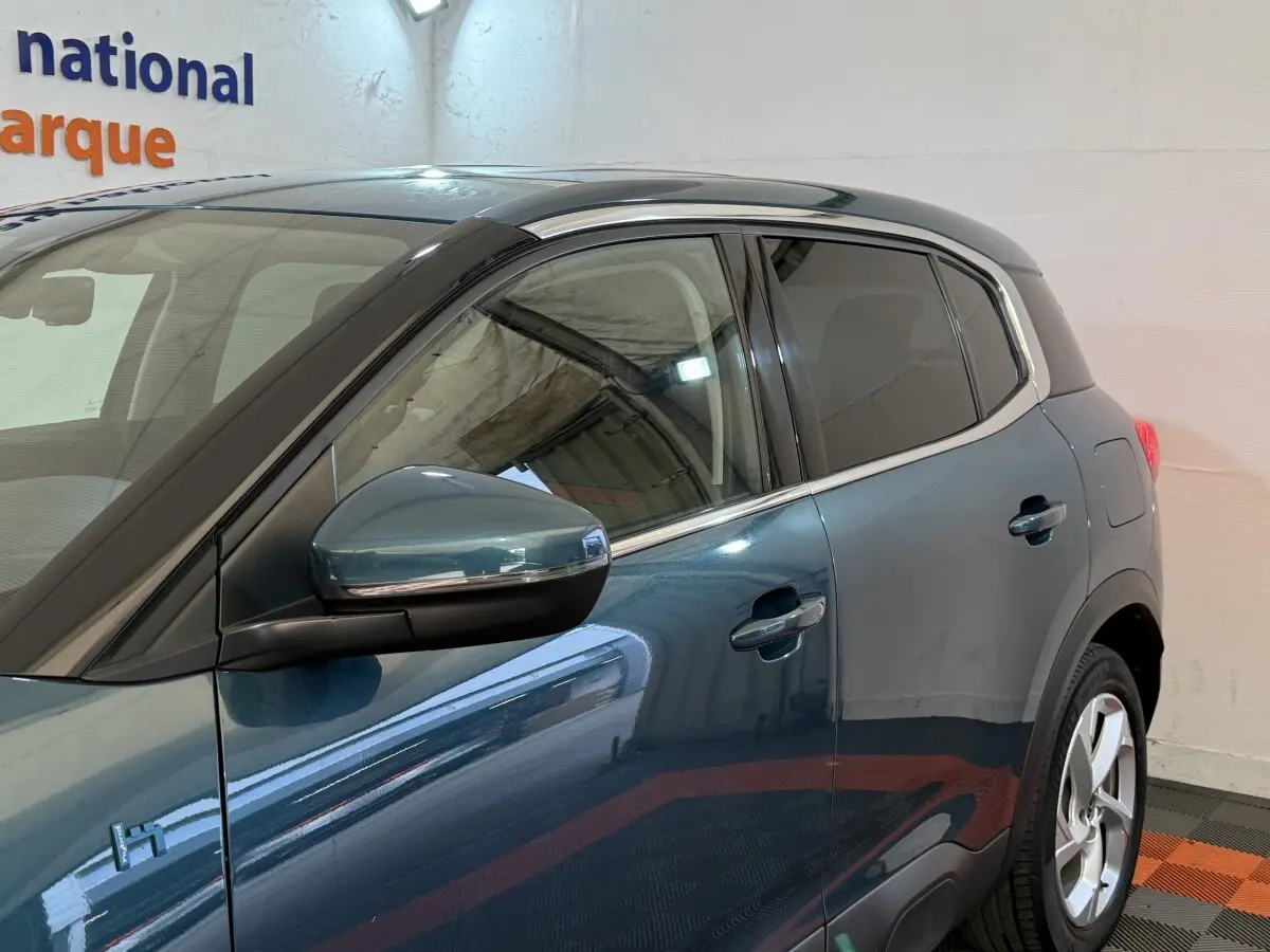 Vue côté gauche arrière du Citroën C5 Aircross Hybrid bleu avec rétroviseur rabattable électriquement et vitres teintées.