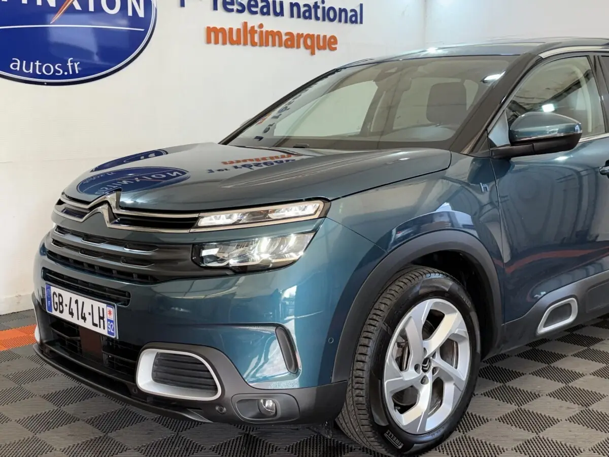 Vue 3/4 avant droit d'un Citroën C5 Aircross Hybrid bleu avec phares LED et jantes alliage distinctives.