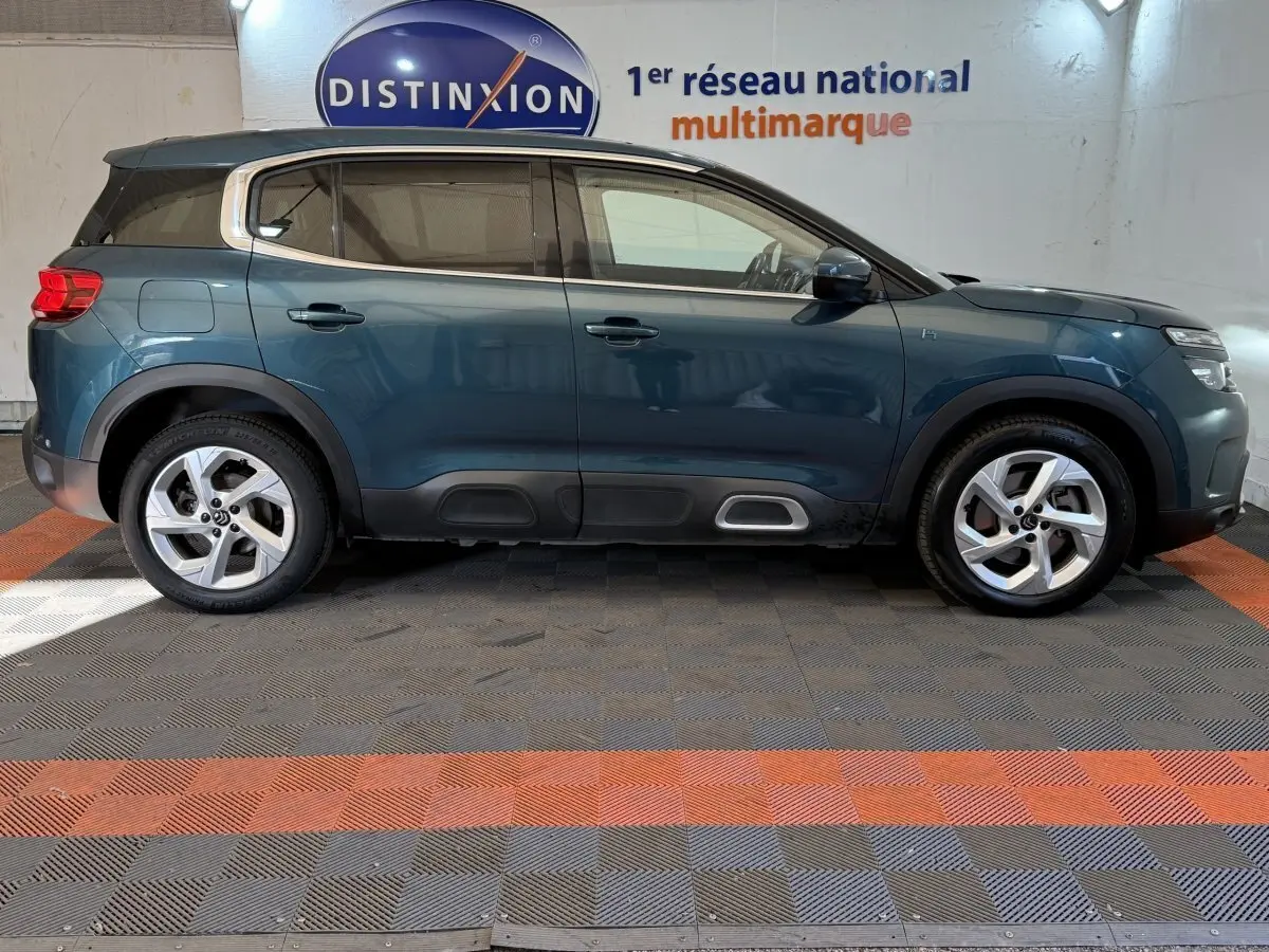 Vue profil droit d'un Citroën C5 Aircross Hybrid 225 bleu, avec jantes alliage et protections noires sur bas de caisse.