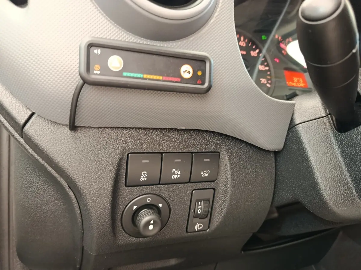 Vue rapprochée du tableau de bord côté gauche du Peugeot Partner blanc, montrant les commandes d'assistance et réglages des phares.