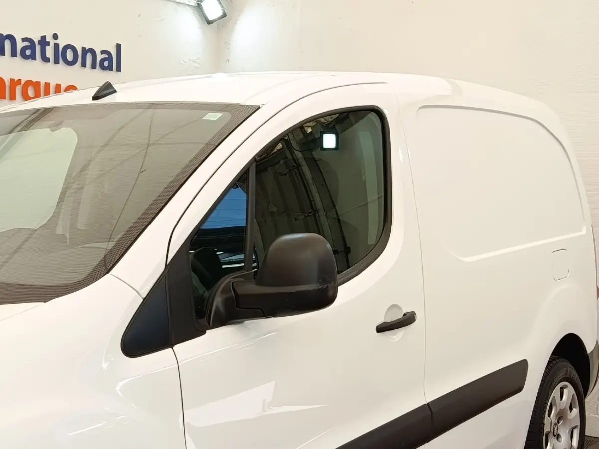 Vue 3/4 avant droit du Peugeot Partner 1.6 BlueHDi 100 Long Pro blanc avec rétroviseur noir et protections latérales noires.
