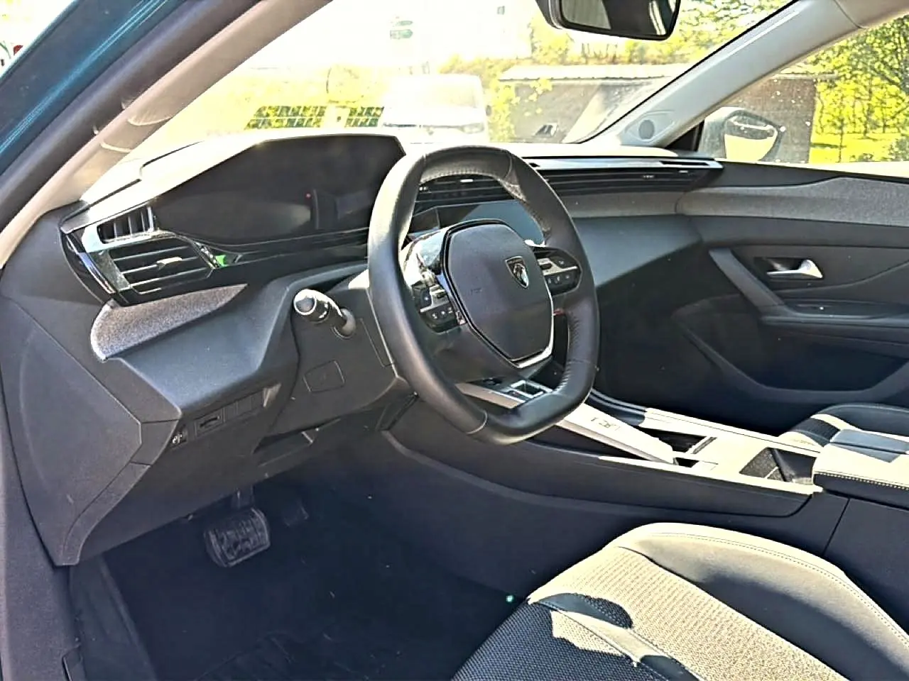 Intérieur de la Peugeot 408 Hybrid 145 allure e-dcs6 vue côté conducteur, volant cuir et tableau de bord moderne.