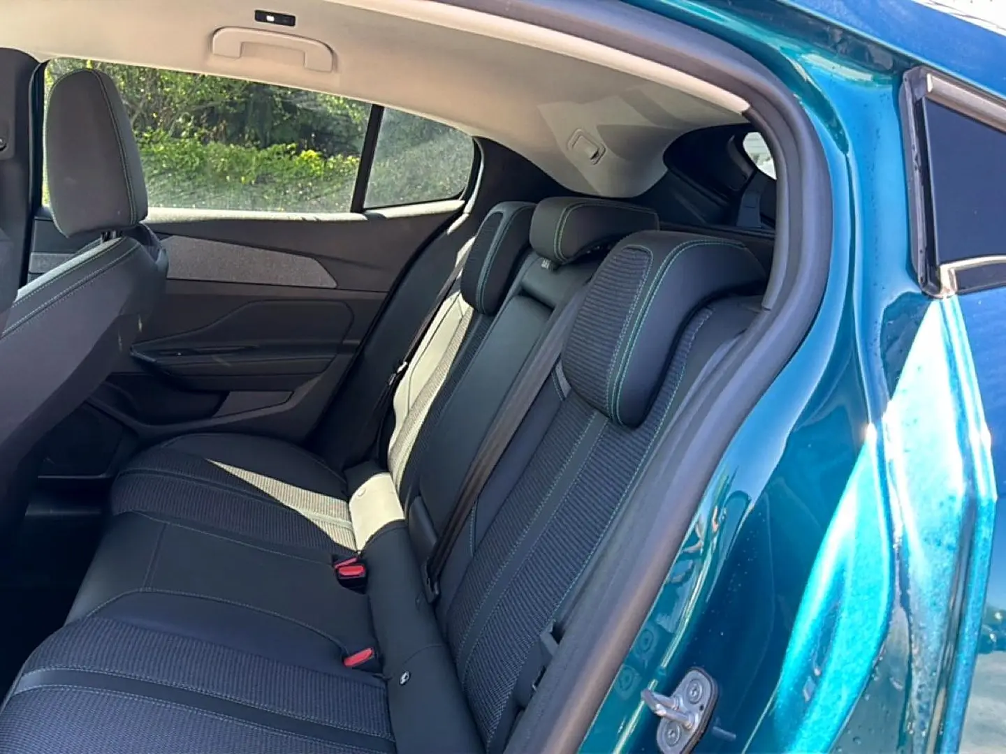 Vue côté gauche sur l’arrière d’une Peugeot 408 Hybrid 145 allure e-dcs6 bleu, montrant la banquette arrière en tissu et cuir.