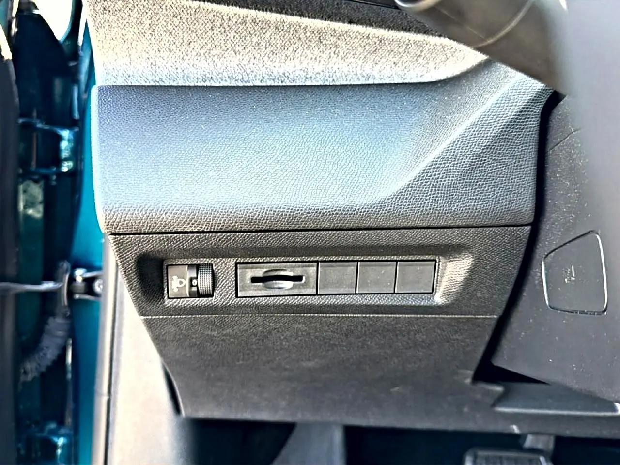 Vue rapprochée du tableau de bord côté gauche d’une Peugeot 408 bleu 2025, avec commandes de réglage des phares.