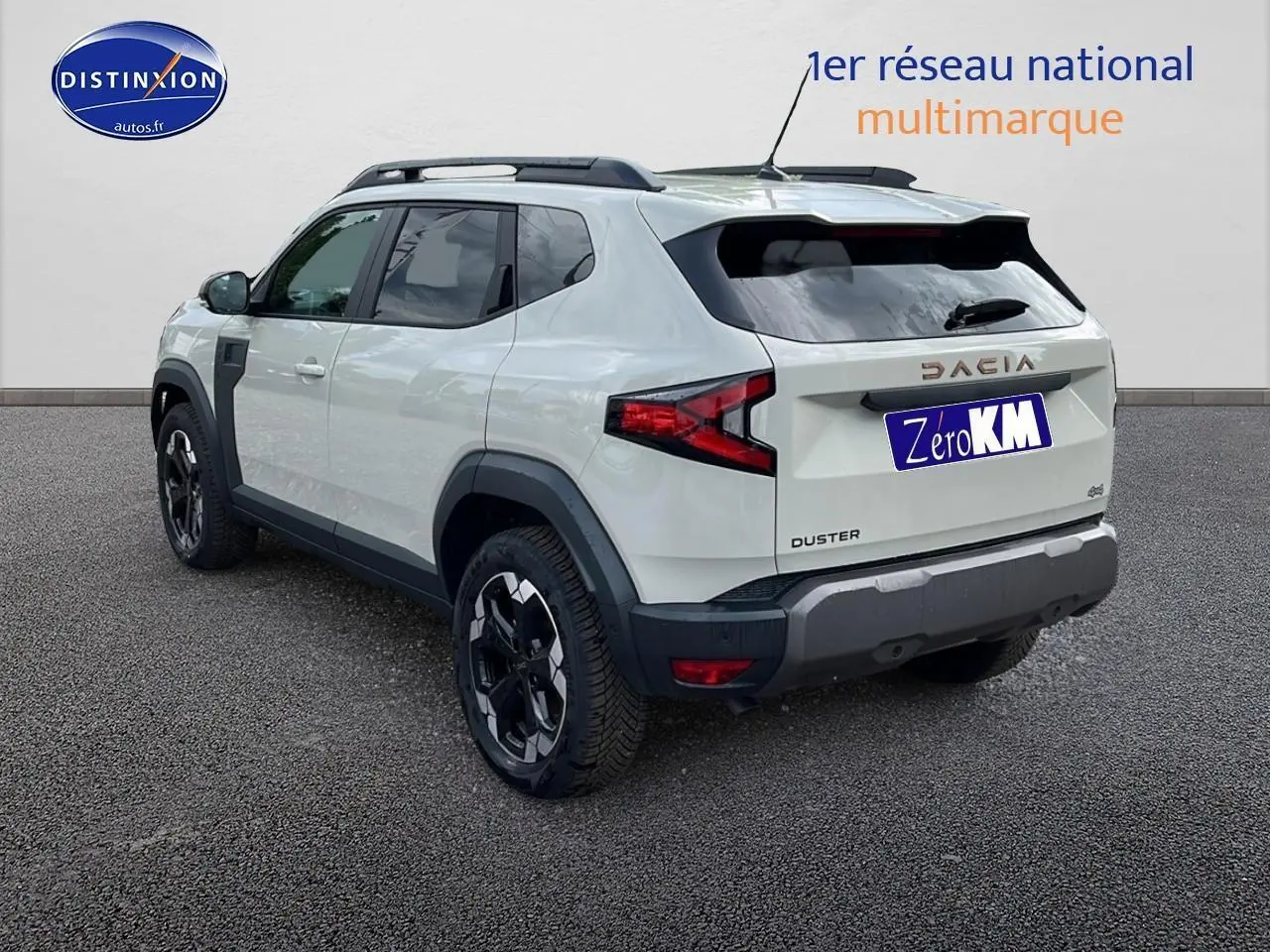 Vue 3/4 arrière droite d'un Dacia Duster 2025 couleur Sandstone avec barres de toit et jantes noires.