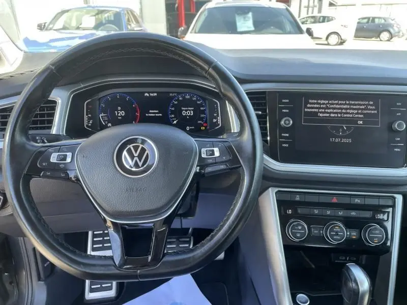 Vue intérieure du volant et tableau de bord du Volkswagen T-Roc gris foncé métal, version 1.5 TSI 150 Active DSG7 de 2021.