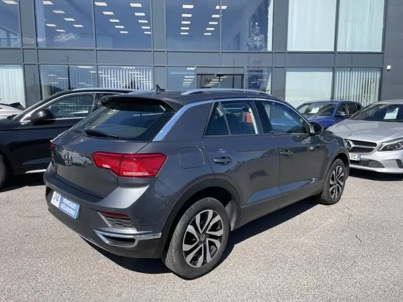 Volkswagen T-Roc gris foncé métal vu de trois quarts arrière droit, avec jantes alliage et toit noir brillant.