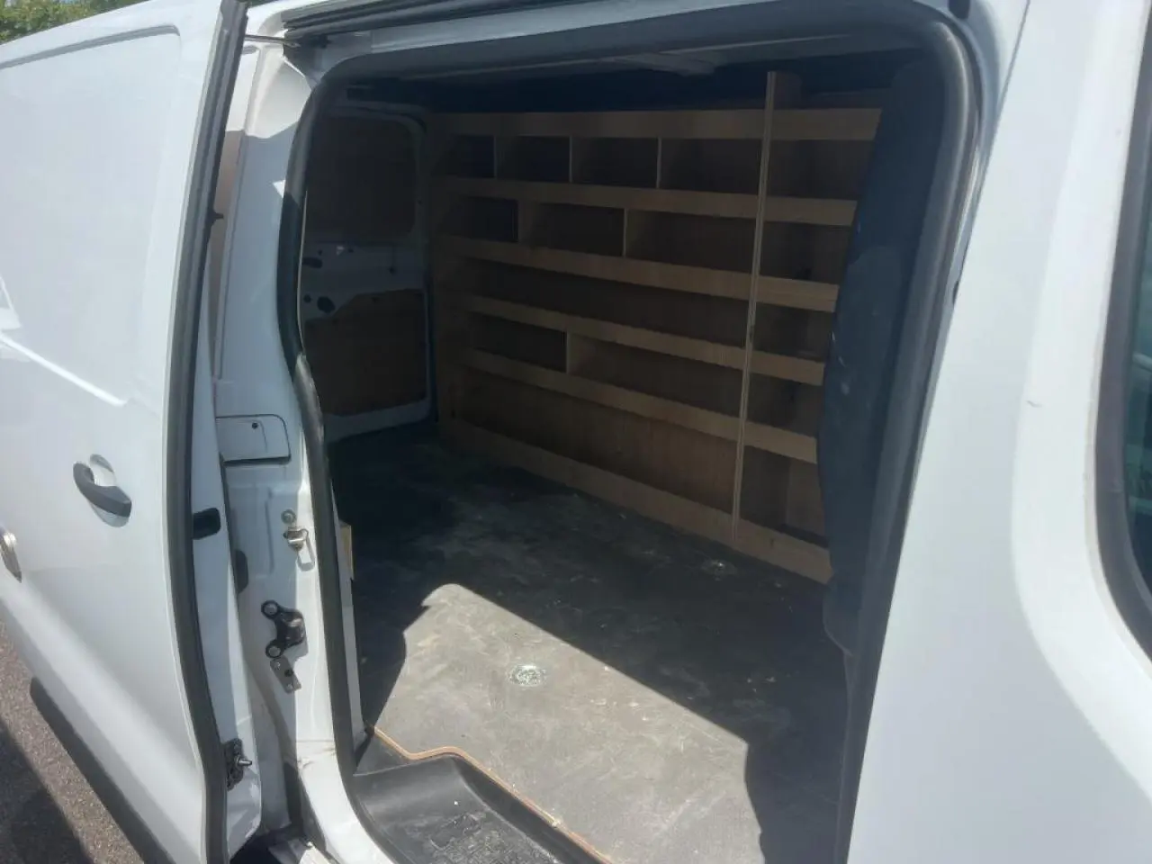 Vue latérale gauche du Citroën Jumpy blanc avec porte coulissante ouverte révélant l'espace de chargement aménagé.