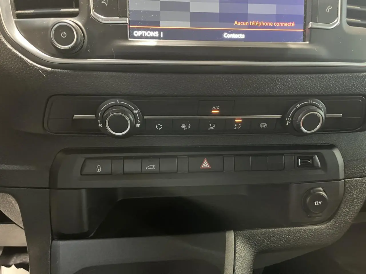 Détail de la console centrale noire du Citroën Jumpy blanc 2023 avec commandes climatisation et prise 12V visible