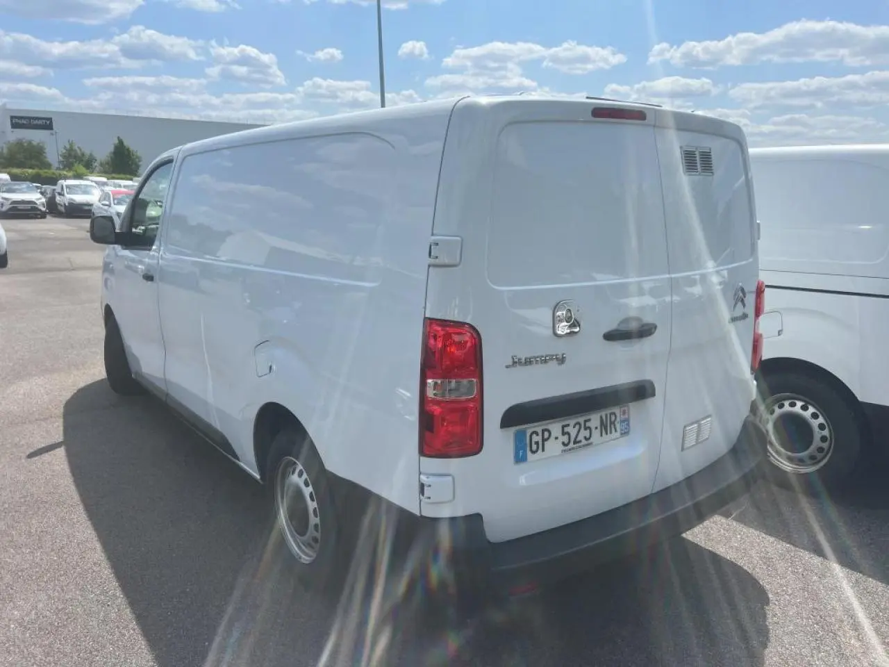 Vue 3/4 arrière droite d'un utilitaire Citroën Jumpy blanc avec portes battantes et jantes tôles grises.