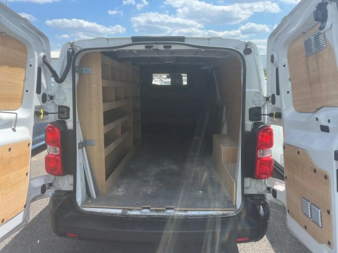 Vue arrière du Citroën Jumpy XL blanc 2023 avec portes battantes ouvertes et aménagements bois dans l'espace de chargement.