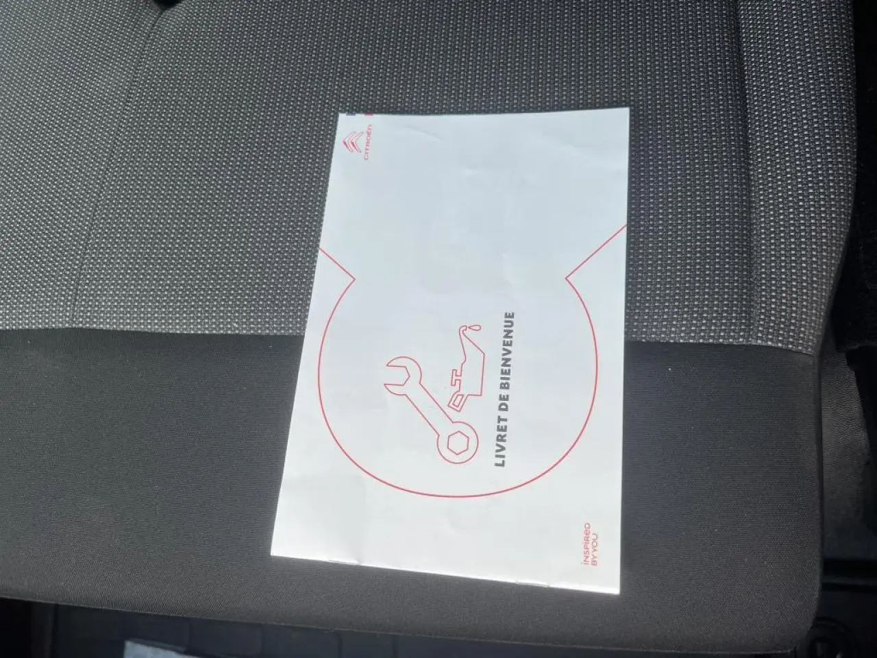 Livret de bienvenue Citroën posé sur siège tissu bi-ton noir et gris du Citroën Jumpy XL blanc 2023.