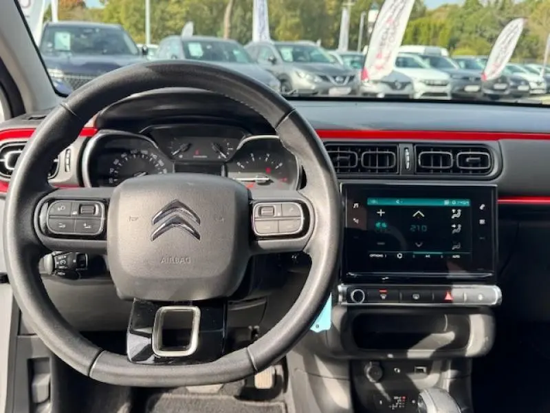 Vue intérieure centrée sur le volant cuir et la tablette tactile du tableau de bord rouge et noir d'une Citroën C3 2017