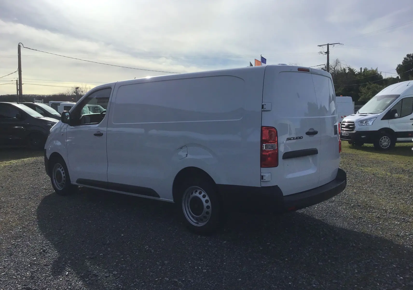 Vue 3/4 arrière droite d’un FIAT Scudo Fourgon blanc 2024 avec garde au sol réhaussée et plaque de protection tôlée.
