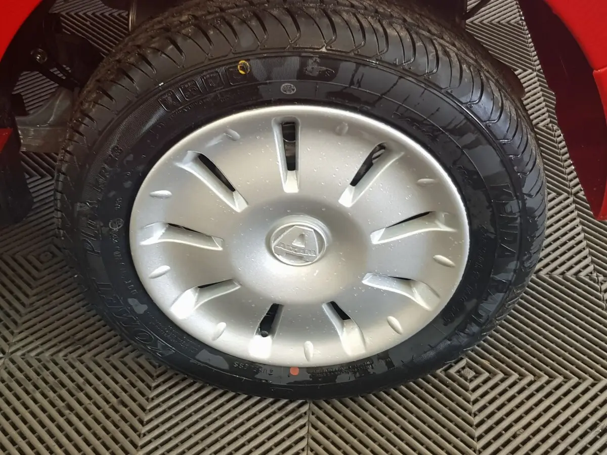 Gros plan sur la roue avant droite de l'AIXAM AMBITION rouge 2026 avec enjoliveur argenté et logo central visible.