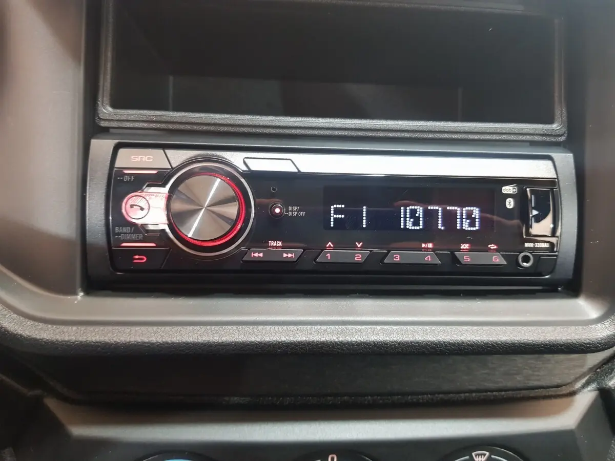 Vue rapprochée de la radio intégrée au tableau de bord de l'AIXAM AMBITION 0.5 CITY PACK rouge, modèle 2026.