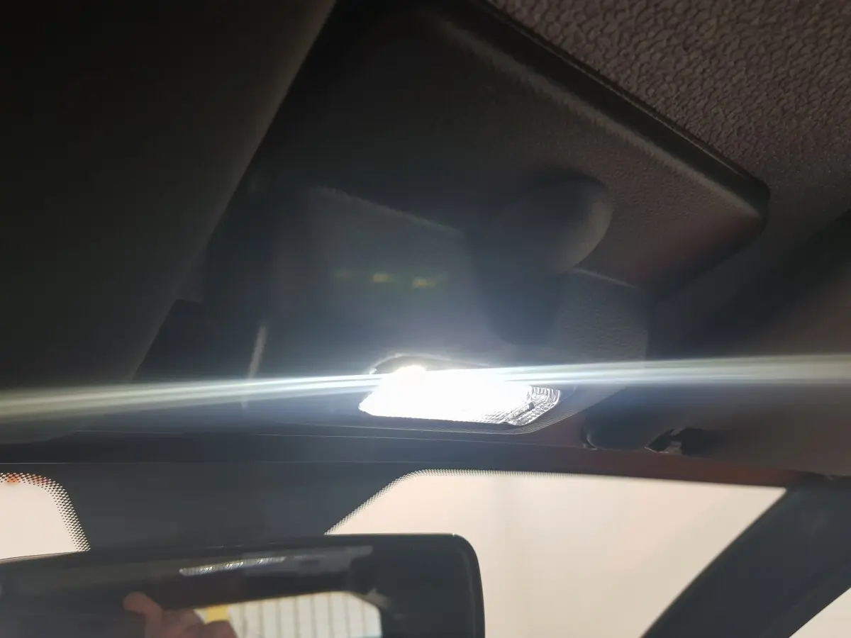 Plafonnier intérieur allumé vu de près sur l'AIXAM AMBITION 0.5 CITY PACK 2026 rouge, avec rétroviseur central visible.