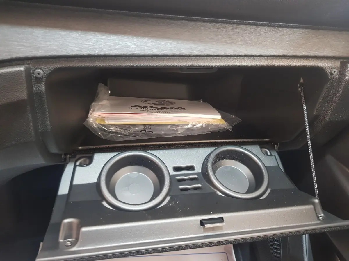 Intérieur de l'AIXAM AMBITION 0.5 CITY PACK 2026 montrant la boîte à gants ouverte avec porte-gobelets intégrés.