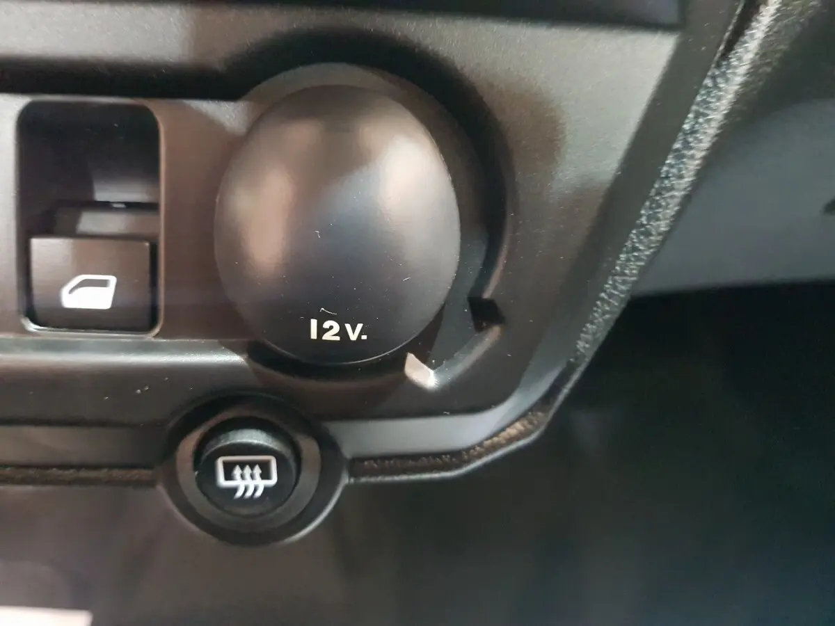 Gros plan sur la prise 12V et le bouton de dégivrage dans l'habitacle de l'AIXAM AMBITION 0.5 CITY PACK.